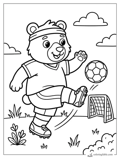 Smiling bear cub in a headband kicks a soccer ball toward a small goal on a grassy field.